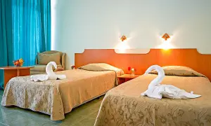 Dwa łóżka w pokoju hotelowym z ręcznikami ułożonymi w kształt łabędzi.