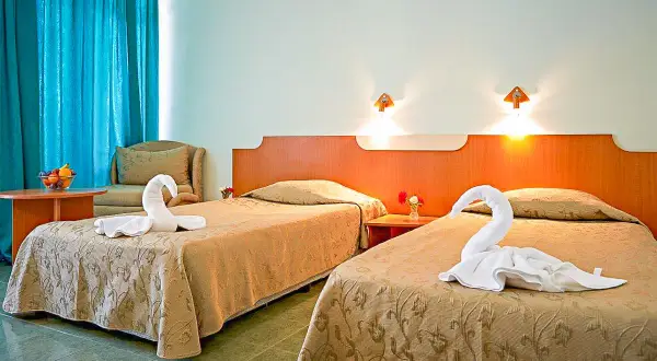 Dwa łóżka w pokoju hotelowym z ręcznikami ułożonymi w kształt łabędzi.
