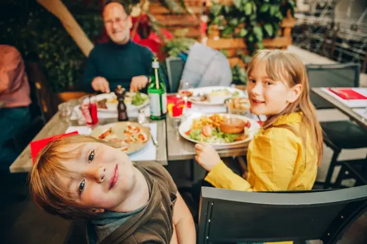 Rodzina jedząca obiad w restauracji z placem zabaw