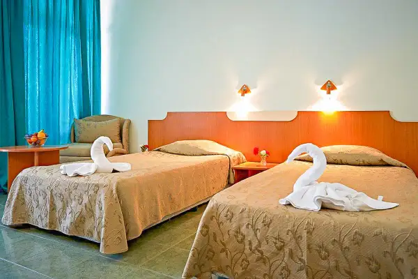 Dwa łóżka w pokoju hotelowym z ręcznikami ułożonymi w kształt łabędzi.